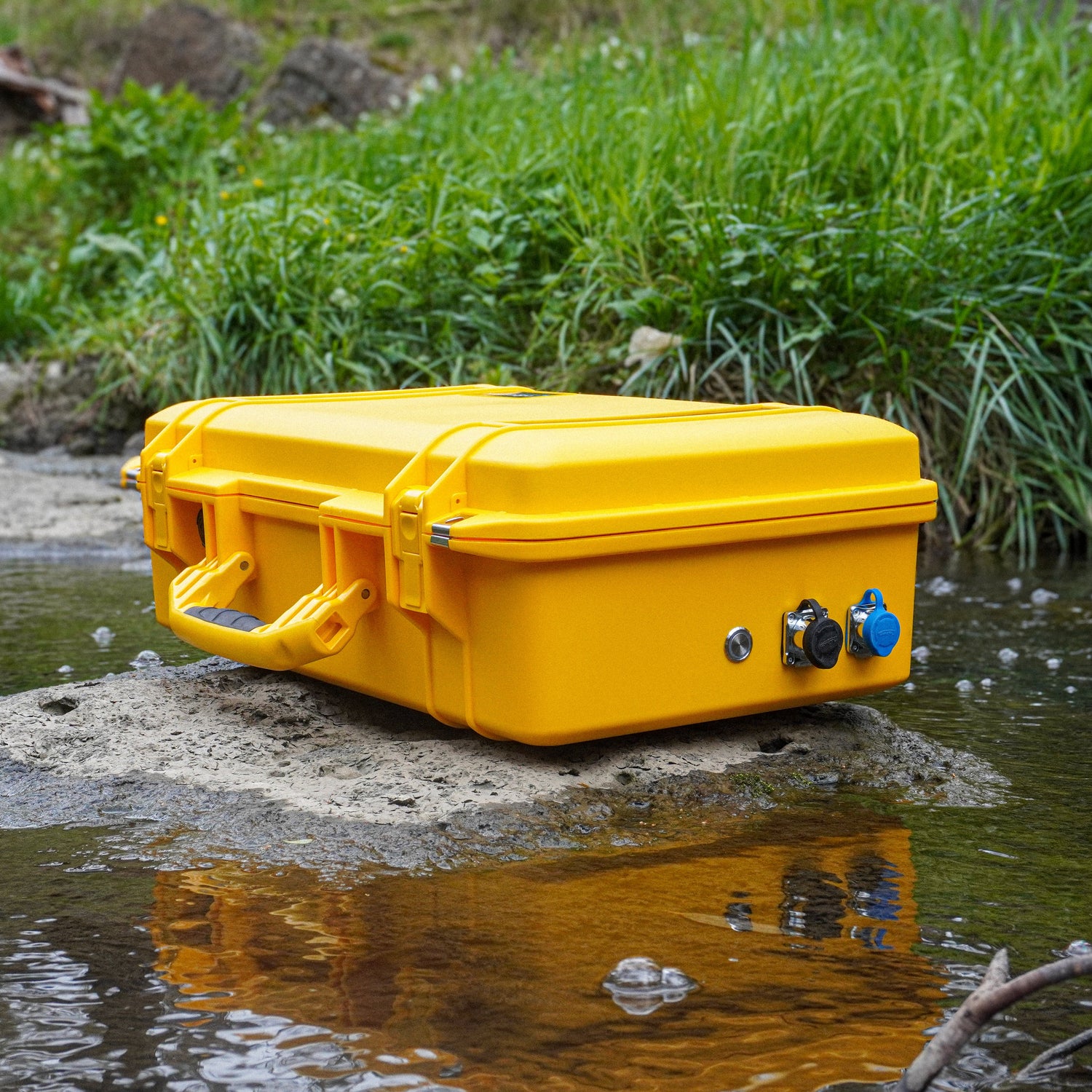 Yellow waterproof case on a rock by a stream